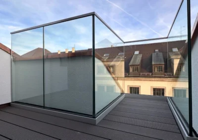 Balkongeländer aus Glas auf einer Terrasse mit Blick über München.