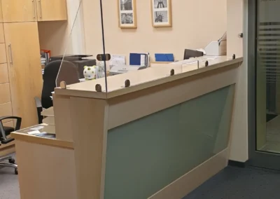 Empfangstheke mit nachgerüsteter transparenter Glasabtrennung in einem Büro.