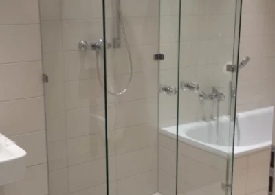 Ganzglasdusche mit transparenten Glaselementen neben einer Badewanne.