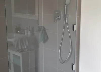 Begehbare Glasdusche mit transparenter Duschverglasung in einem Badezimmer in Grünwald.