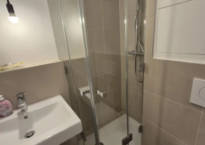 Maßgefertigte Glasdusche mit transparenter Duschabtrennung in einem kleinen Badezimmer.