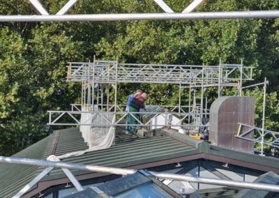 Monteure begutachten eine Dachverglasung auf einem Gerüst vor der Reparatur.