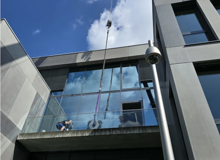 Monteure arbeiten an einer modernen Glasfassade eines Wohn- oder Gewerbegebäudes.