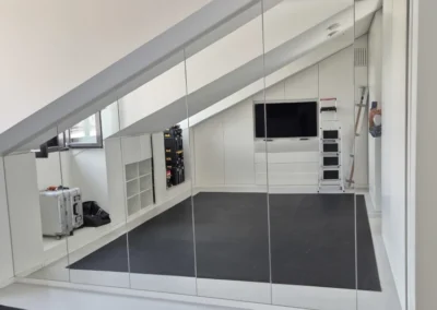 Große Spiegelwand unter einer Dachschräge in einem hellen Raum.